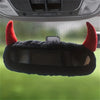 A black devil horn rearview mirror cover with red accents shown against a green background.
