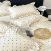 A set of three white bedding pillows and a duvet cover with a black dot print, displayed on a bed.