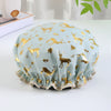 Light blue reusable elastic shower cap patterned with gold deer and foliage designs
