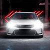 A white car with red interior is shown in a dark setting, featuring bright LED headlights and red accent lights.