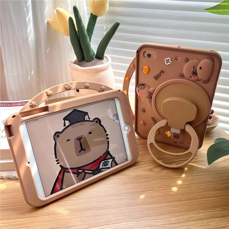 A beige silicone case for an iPad featuring a cute cartoon bear design, placed next to a phone case and yellow tulips.