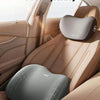 Interior view of a car seat showing first class comfort headrest and lumbar support pillows in beige leather.
