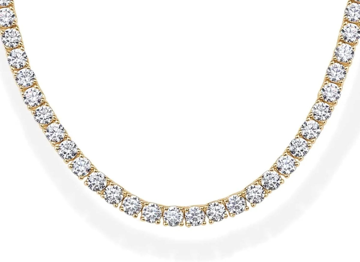 A close-up of a simulated diamond tennis necklace with a gold setting and white diamonds.