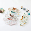 A collection of six-layer cotton baby feeding bibs in various floral patterns and a small stuffed animal