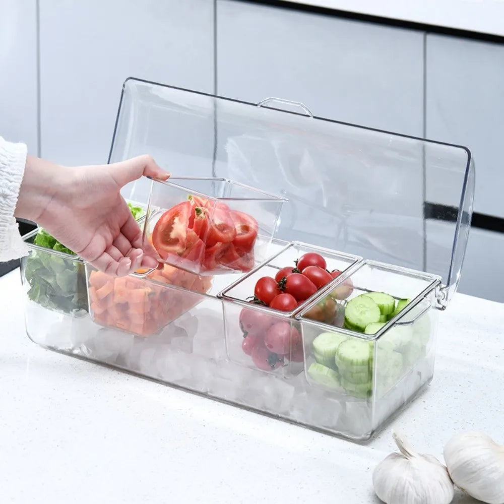 A hand is placing fresh tomatoes and greens into a clear 5-compartment chilled condiment server with an ice base.