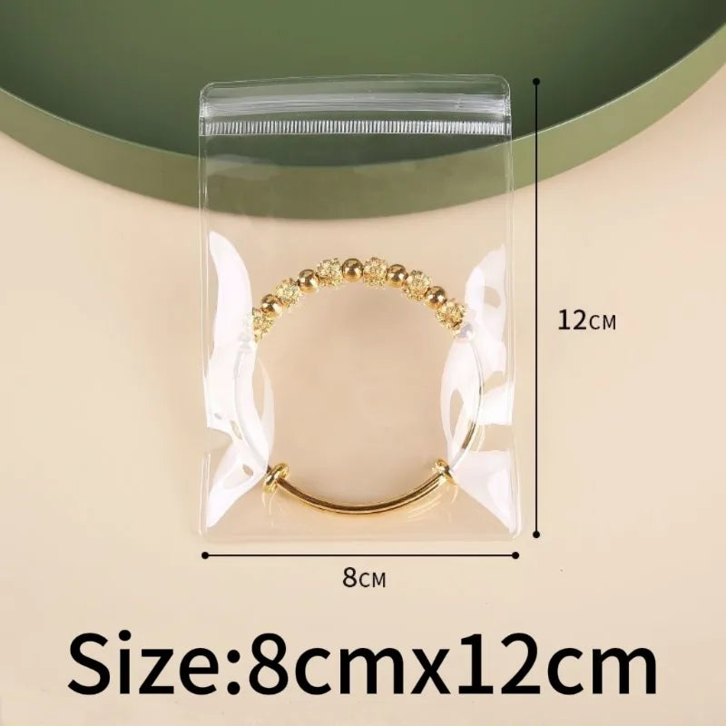 A clear self-sealing jewelry storage bag containing a gold-toned beaded bracelet.