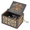 A dark wooden music box with gold accents and an engraved crown design, featuring a hand crank mechanism.