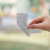 Eine Hand appliziert Reparaturtape auf ein Fenstergitternetz.