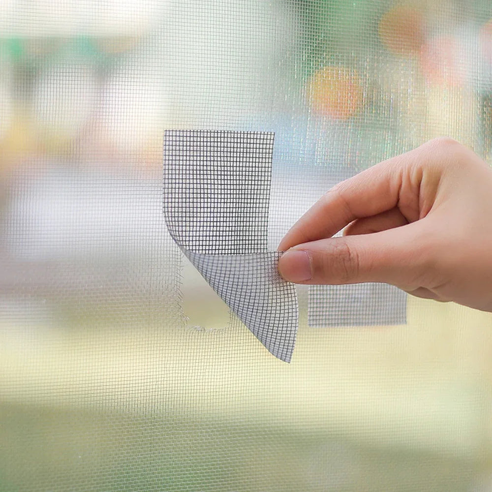 Eine Hand appliziert Reparaturtape auf ein Fenstergitternetz.