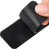 A close-up of a black double-sided adhesive carpet and mat fixing patch being held by a hand.