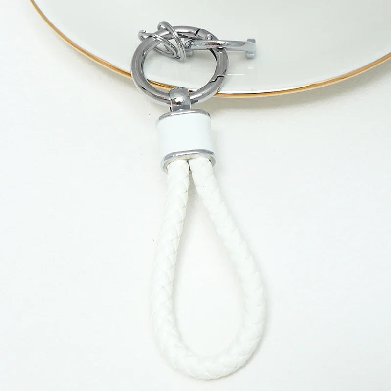 Silver key fob cover with a white braided cord attached, resting on a white surface.