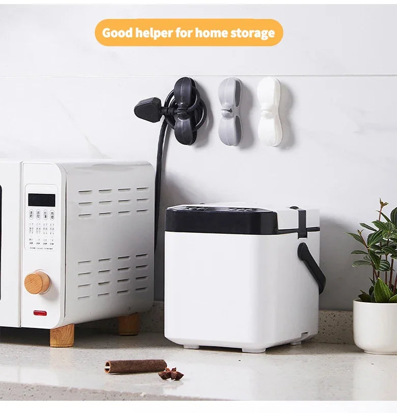 A white cord organizer and wire winder device is mounted on a wall next to a white appliance.