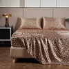 Luxury satin leopard print bedding set displayed on a bed with neutral tones.