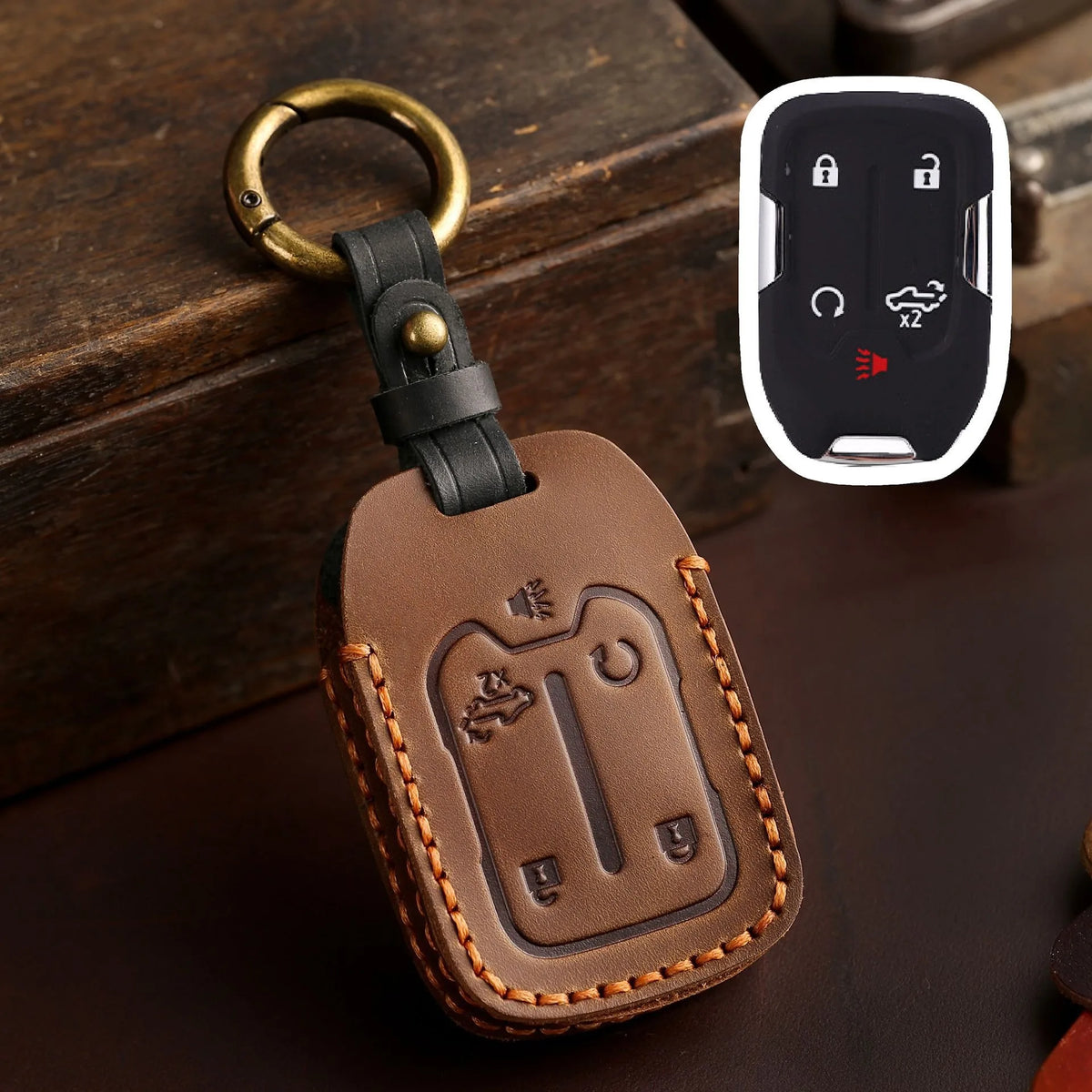 Brown leather key fob case with a brass ring attached, featuring cutouts for Chevrolet and GMC keys.