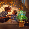 A smiling mother and child are interacting with a glowing green dancing cactus plush toy decorated with musical notes.