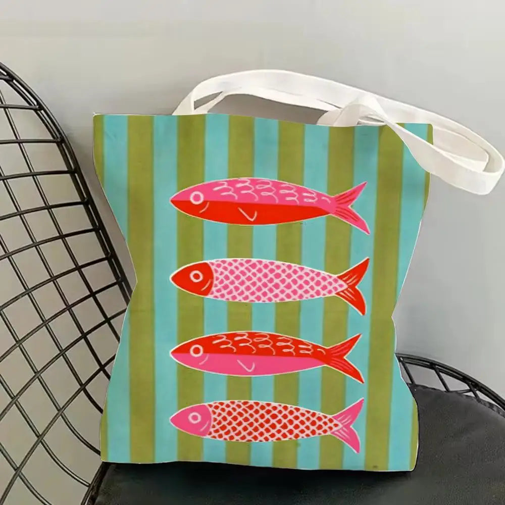 A canvas tote bag featuring a vertical striped pattern with colorful fish prints.
