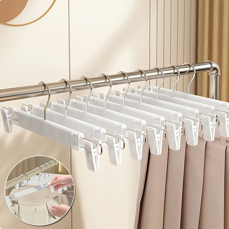 Silver clip hangers for pants, skirts, and trousers hanging on a rod.