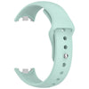 A light mint green silicone replacement strap for a fitness tracker, shown in a curved form.