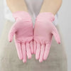 A pair of disposable pink nitrile gloves being held up against a white background.