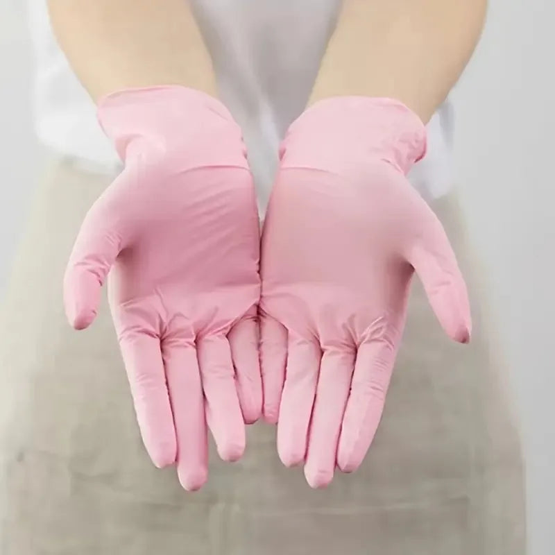 A pair of disposable pink nitrile gloves being held up against a white background.