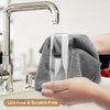 A hand is wiping a glass faucet with a gray microfiber cleaning wipe.