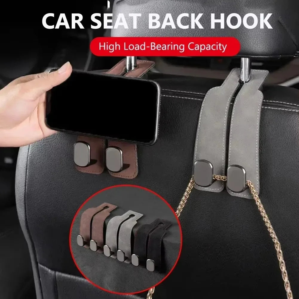 A hand is attaching a dual suede hook car seat back storage hook to a black car seat for securing bags.
