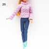 A fashion doll wearing a pink patterned knit turtleneck sweater and dark blue pants.