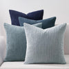 A collection of navy blue and light blue corduroy throw pillows on a white sofa.