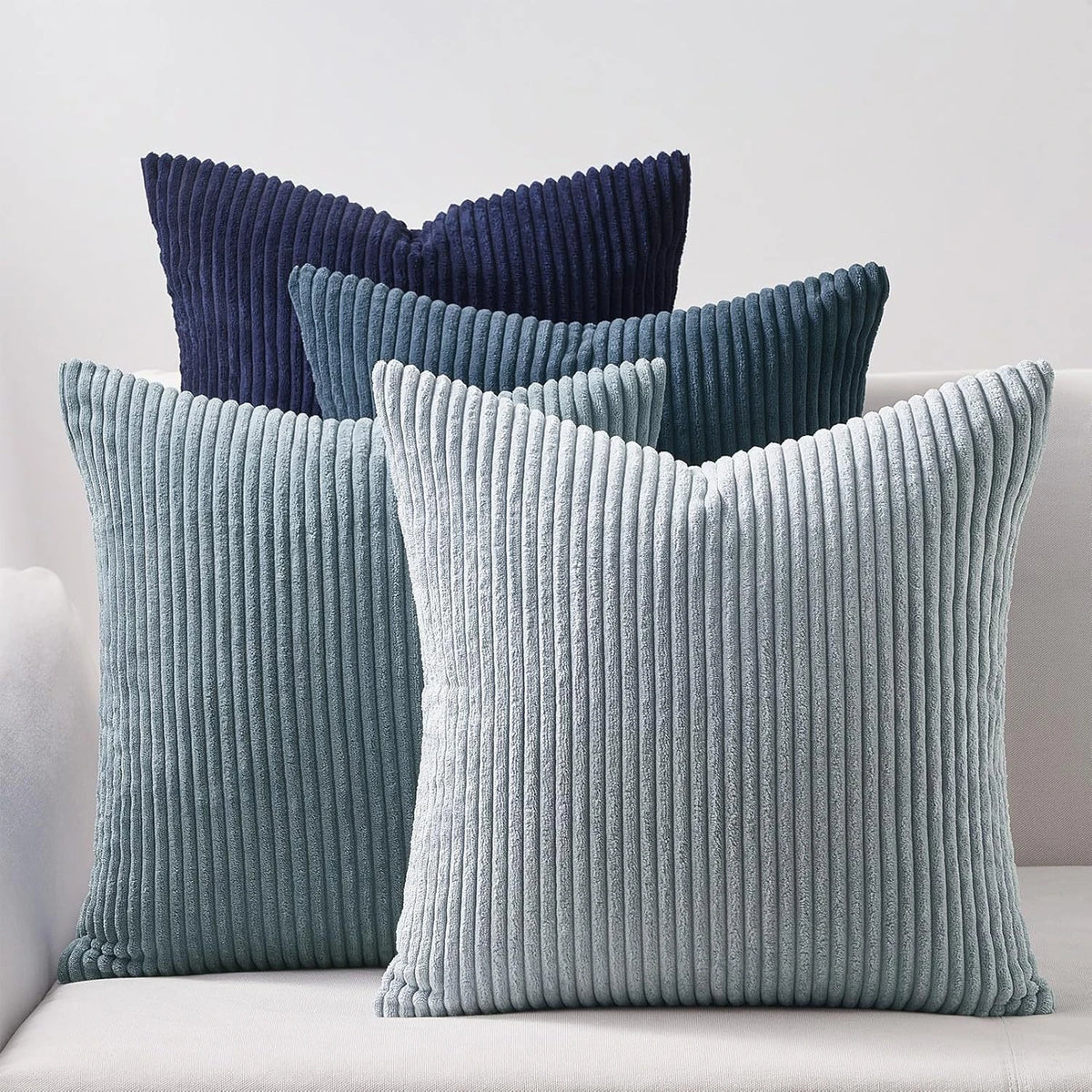 A collection of navy blue and light blue corduroy throw pillows on a white sofa.