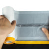 A hand is holding a roll of static-cling clear plastic sheeting for painting and protection.