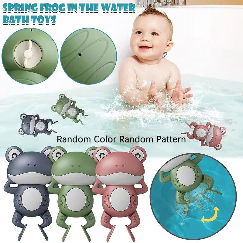 A baby is playing with a green wind-up swimming frog bath toy in water, surrounded by various frog toys.