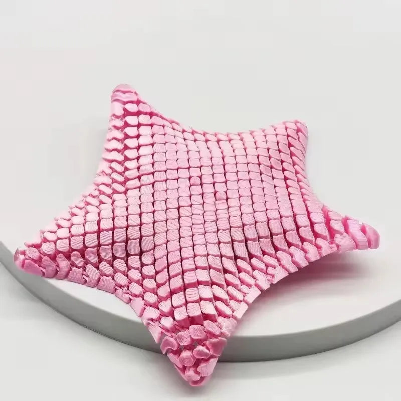 A pink 3D printed articulated starfish fidget toy with a textured, quilted surface.