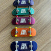 A stack of five wooden fingerboard skateboards in various colors including purple, green, magenta, orange, and blue.