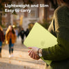A person holds a light green laptop in a protective hard shell case while walking outdoors.