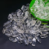Clear crystal stone chips and tumbled stones in a green bowl on a dark surface
