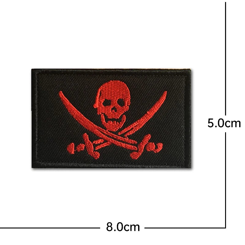 Black embroidered patch featuring a red skull and crossed swords design with hook and loop backing