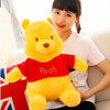 A young woman is holding a yellow Winnie the Pooh plush toy with a red shirt.