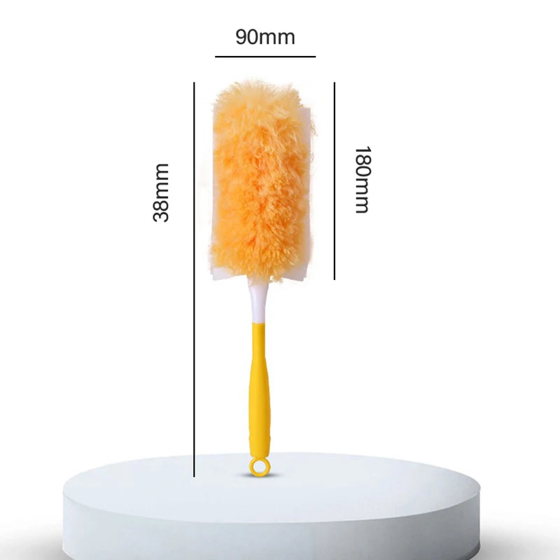 A yellow electrostatic duster with an orange fluffy head is shown standing on a white circular platform.