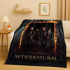 A dark themed throw blanket featuring characters from the Supernatural TV show against a fiery background.