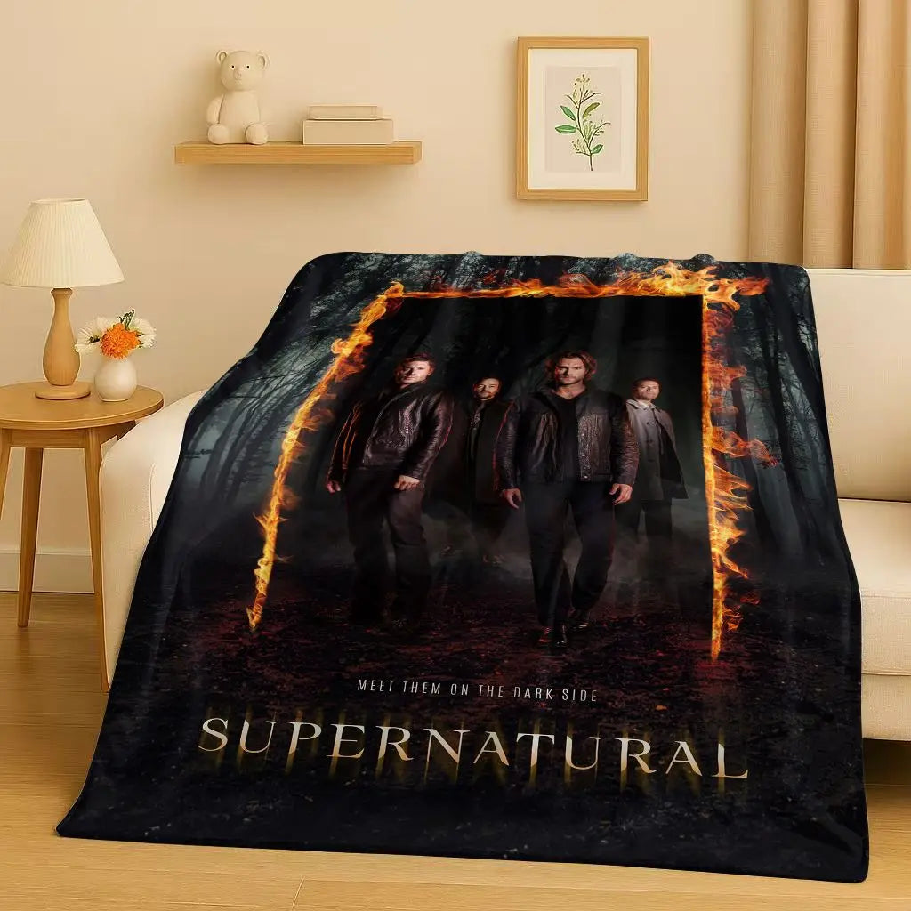 A dark themed throw blanket featuring characters from the Supernatural TV show against a fiery background.