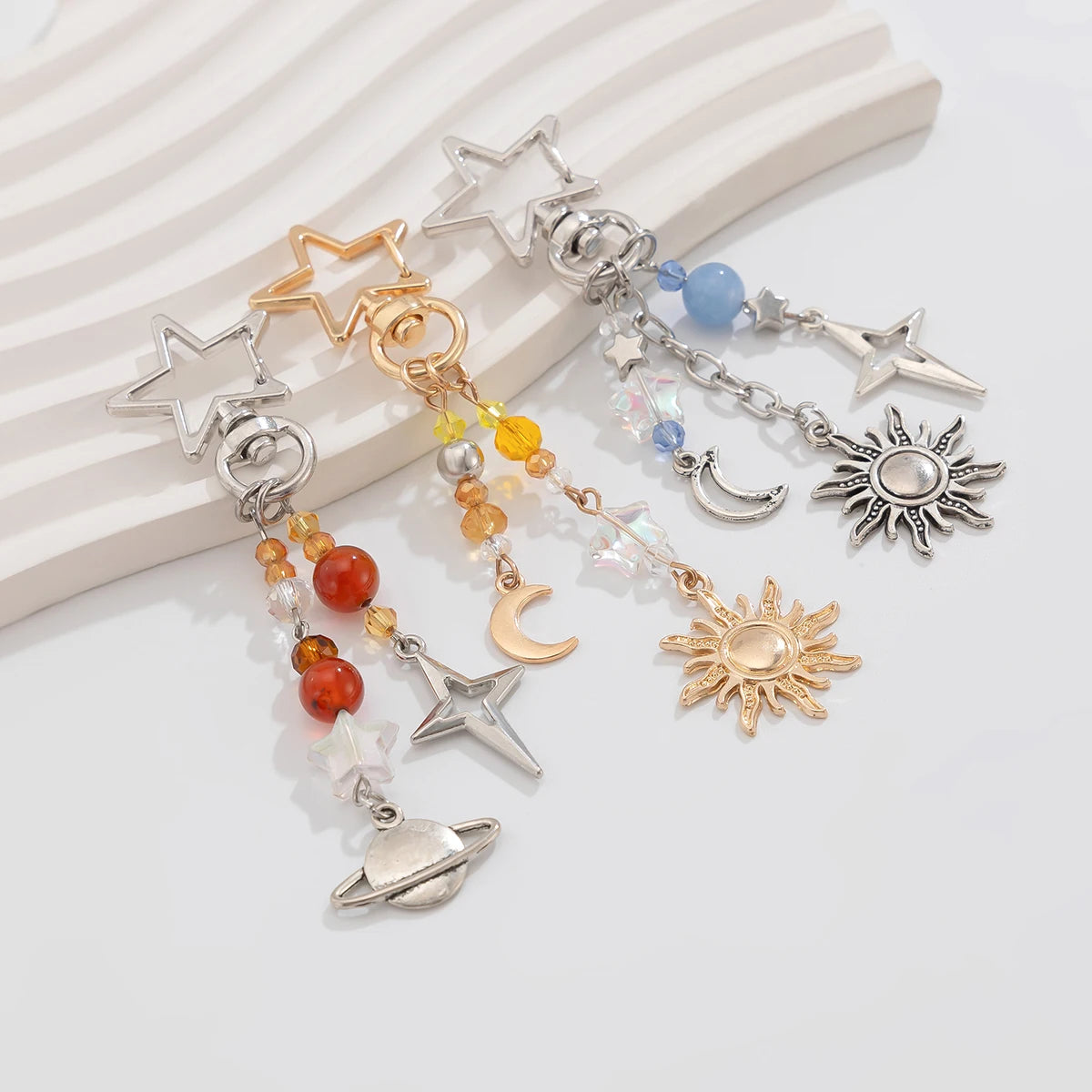 Un ensemble de clés en perles bohèmes célestes avec étoiles, lunes et soleils dans des tons argent et or.