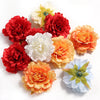 A collection of silk peony flower heads in shades of red, orange, and white.