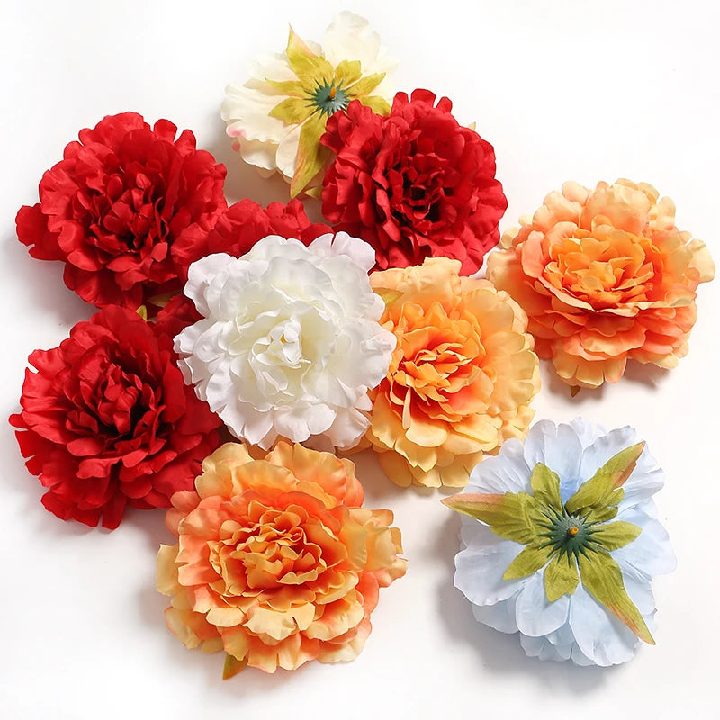 A collection of silk peony flower heads in shades of red, orange, and white.