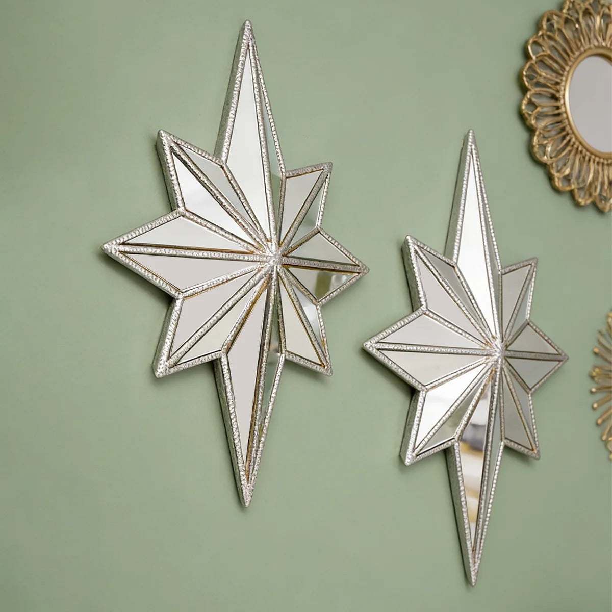 A pair of silver octagonal star resin wall mirrors with gold trim displayed against a muted green background.