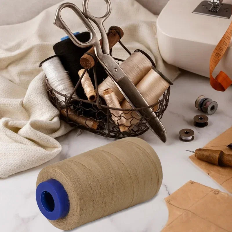 A collection of sewing scissors and spools of beige polyester thread are displayed on a white surface.