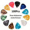 A collection of 100 assorted guitar picks in various colors and three thicknesses, including red, black, blue, green, gold, a