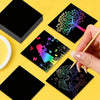 A set of black art paper sheets featuring colorful rainbow designs and a wooden stylus being held by a hand.