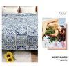 A blue and white patchwork cotton bedspread with floral patterns displayed next to a yellow flower.
