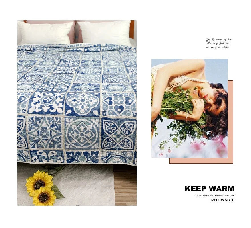 A blue and white patchwork cotton bedspread with floral patterns displayed next to a yellow flower.