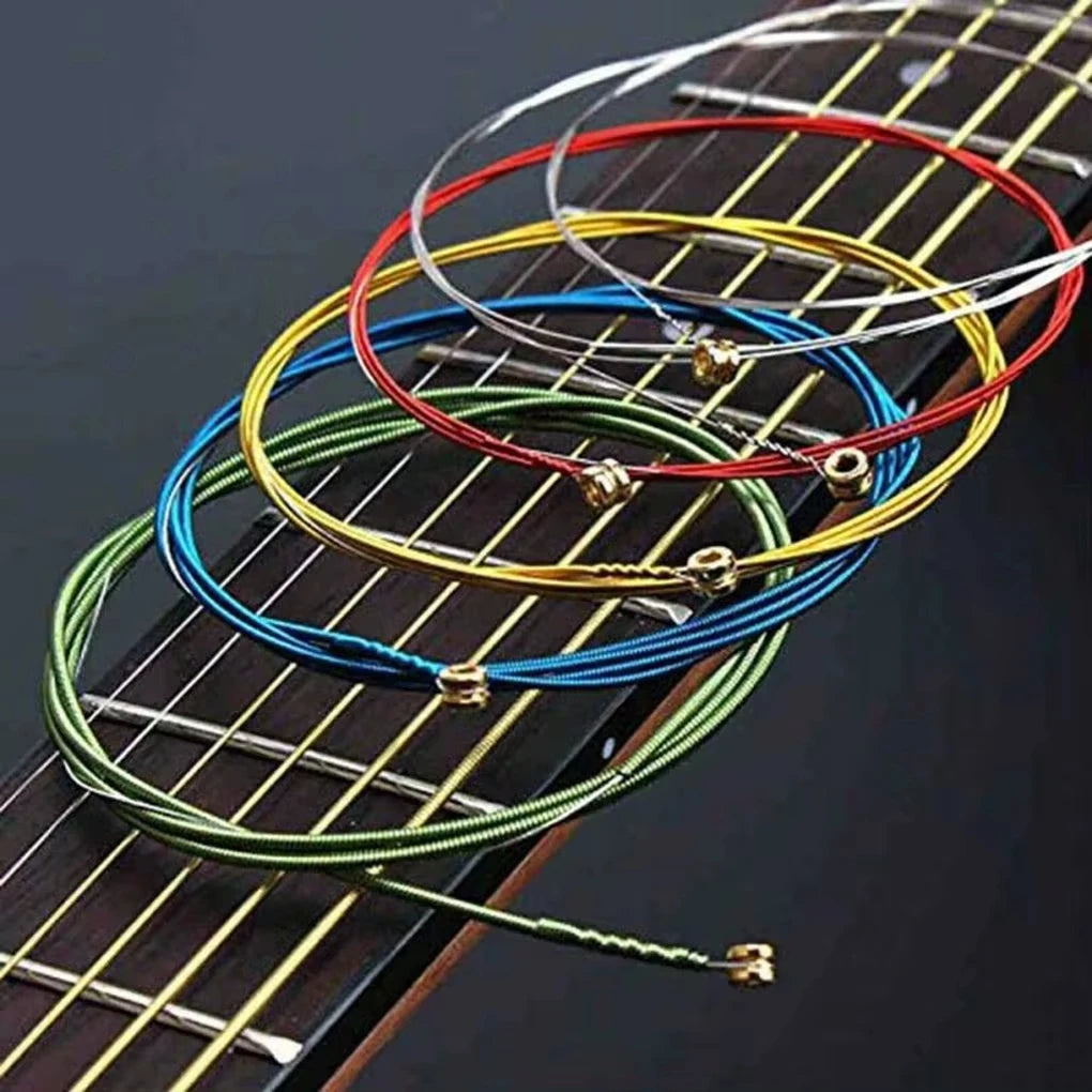 A close-up view of six color-coded acoustic guitar strings laid out on a wooden fretboard.